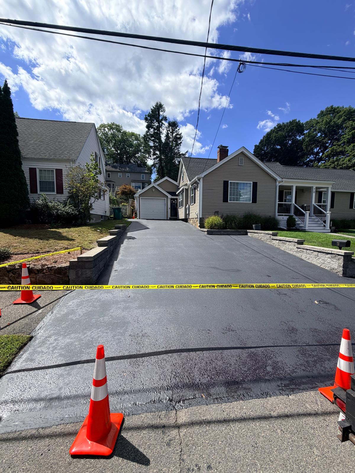 Completed residential driveway sealcoating in bright daylight