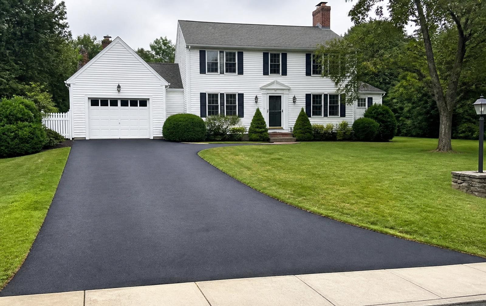 After: the same driveway with a deep black, freshly sealcoated finish