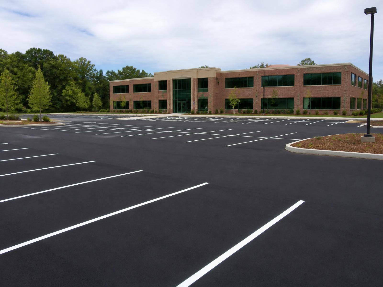 Newly sealed and striped commercial parking lot in front of an office building